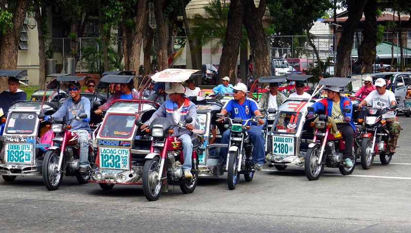 Multiple tricycle motorcycles at a stop light.